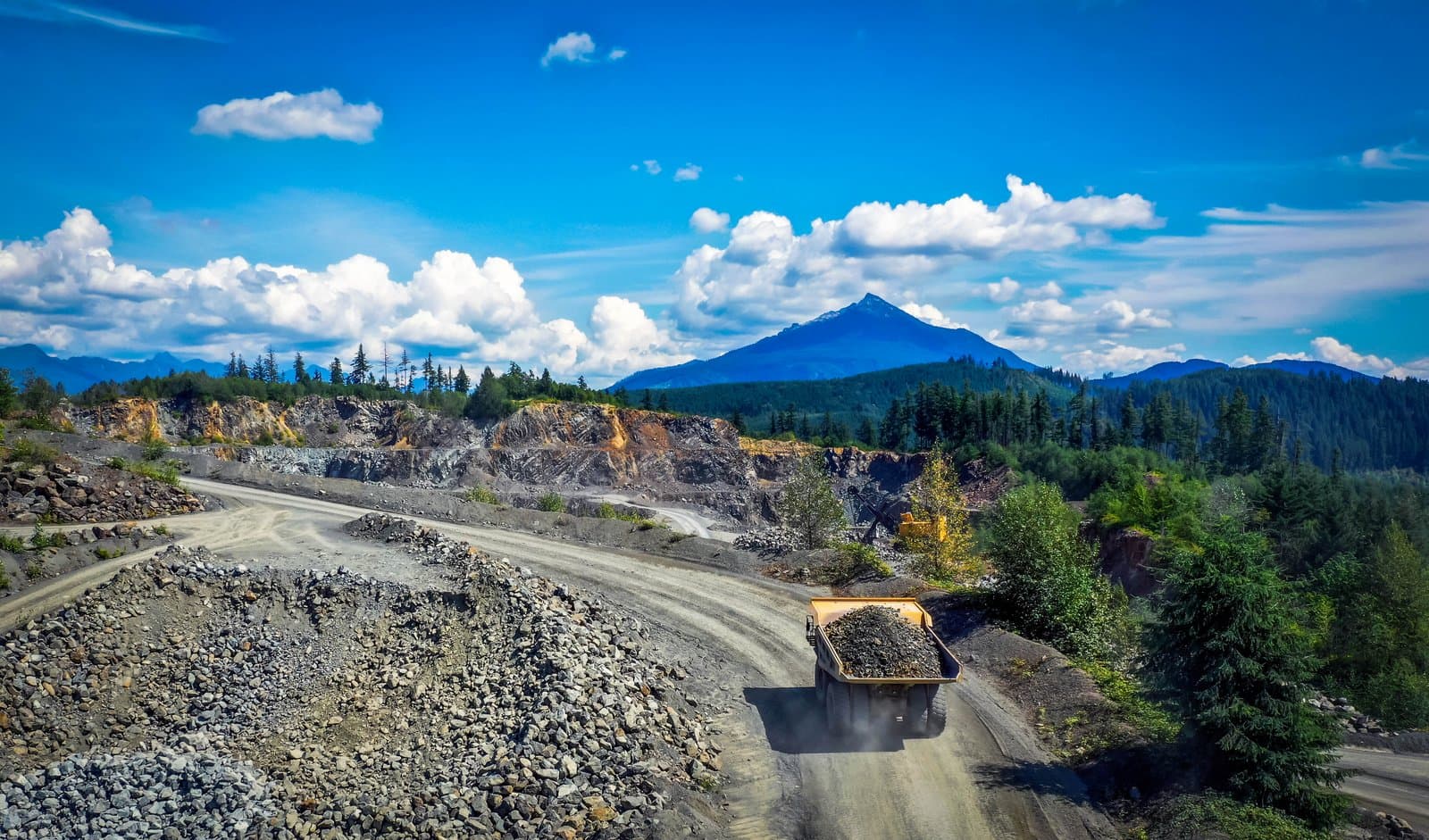 A loaded haul truck on the quarry haul road, the Cascade peak beyond.
