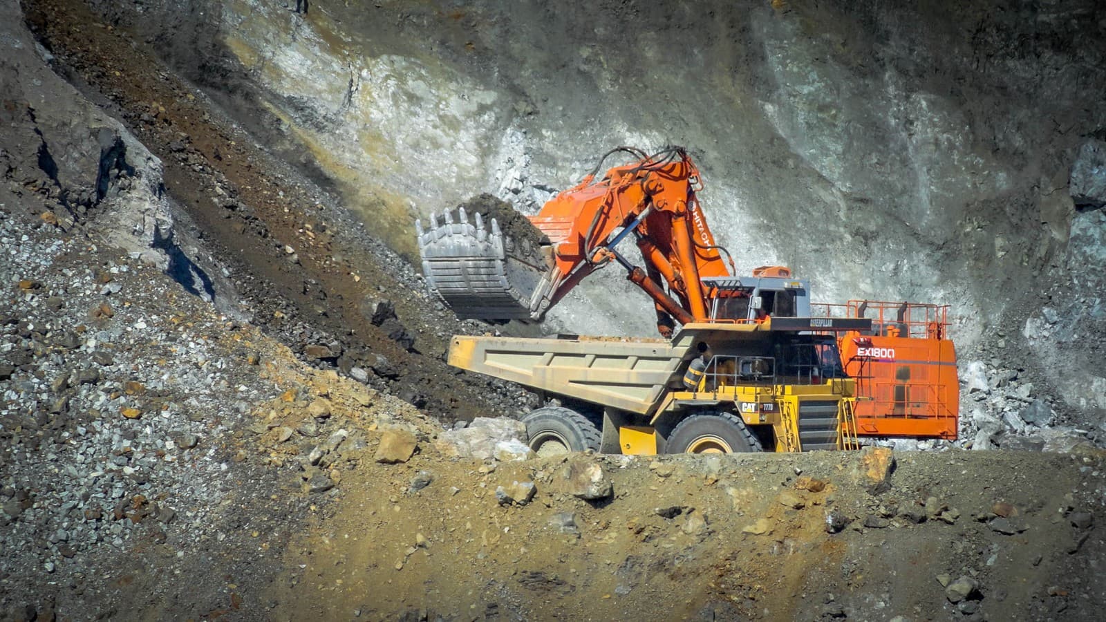 An excavator working a raw rock ledge face in the quarry.
